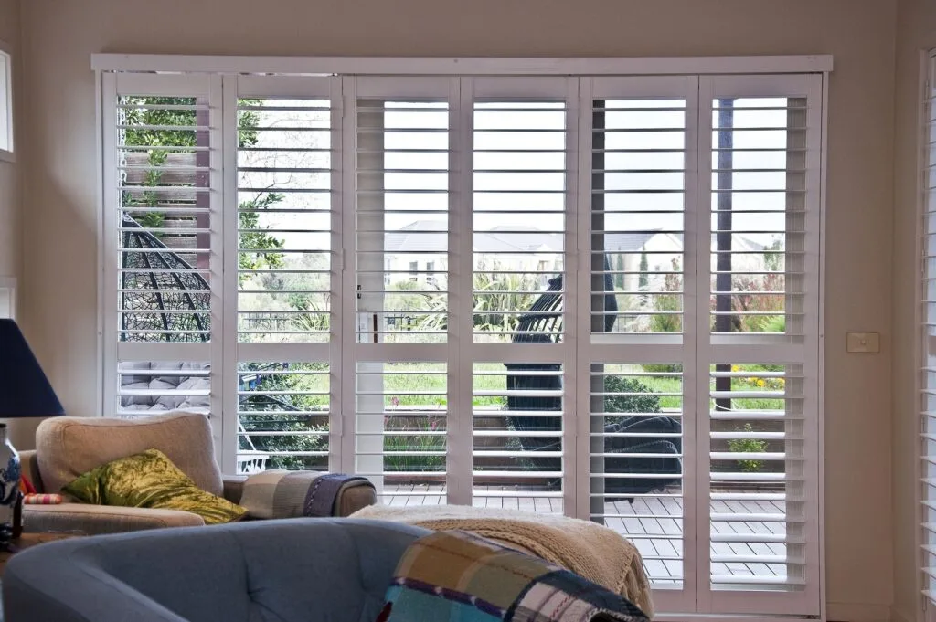 White plantation shutters installed across a wide living room opening